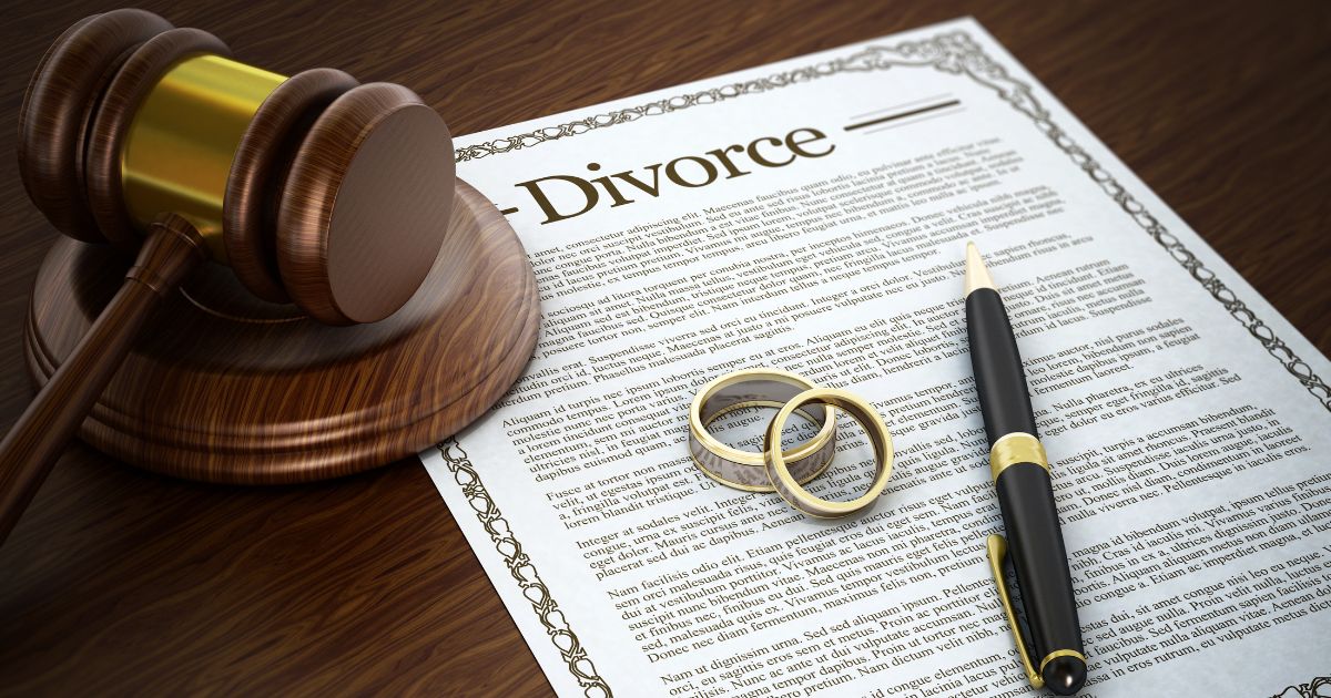 Divorce decree with gavel, pen, and wedding rings