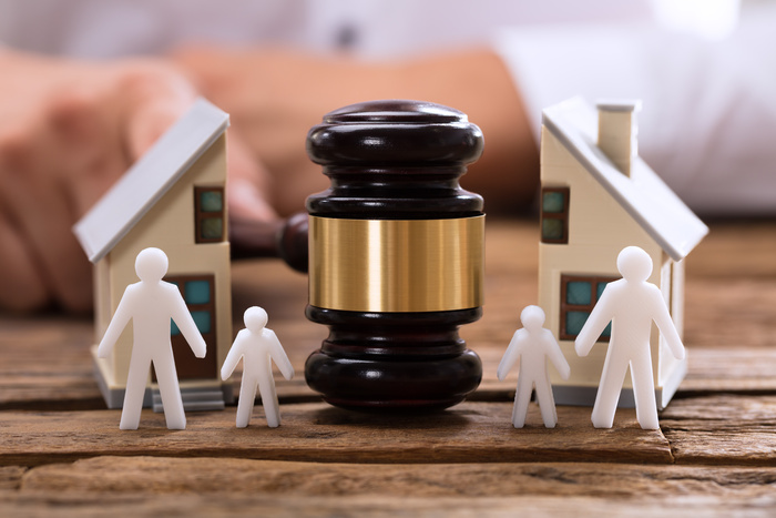 Close-up of mallet showing separation of family and house on wooden desk - Family law firm
