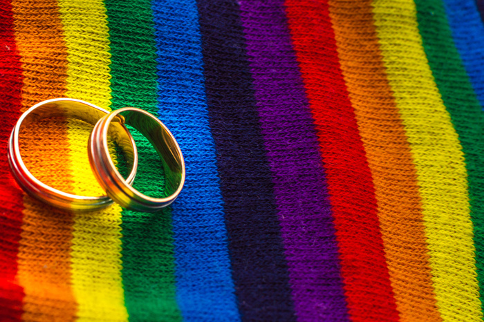 Two wedding rings on the fabric colors of the rainbow. Concept same-sex marriage.